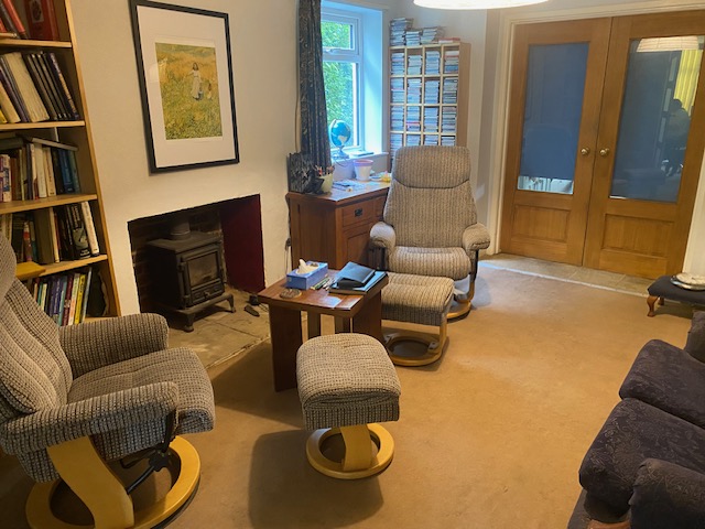 Lindy's counselling room in Trowbridge - a calm, comfortable space with armchairs and a woodburner